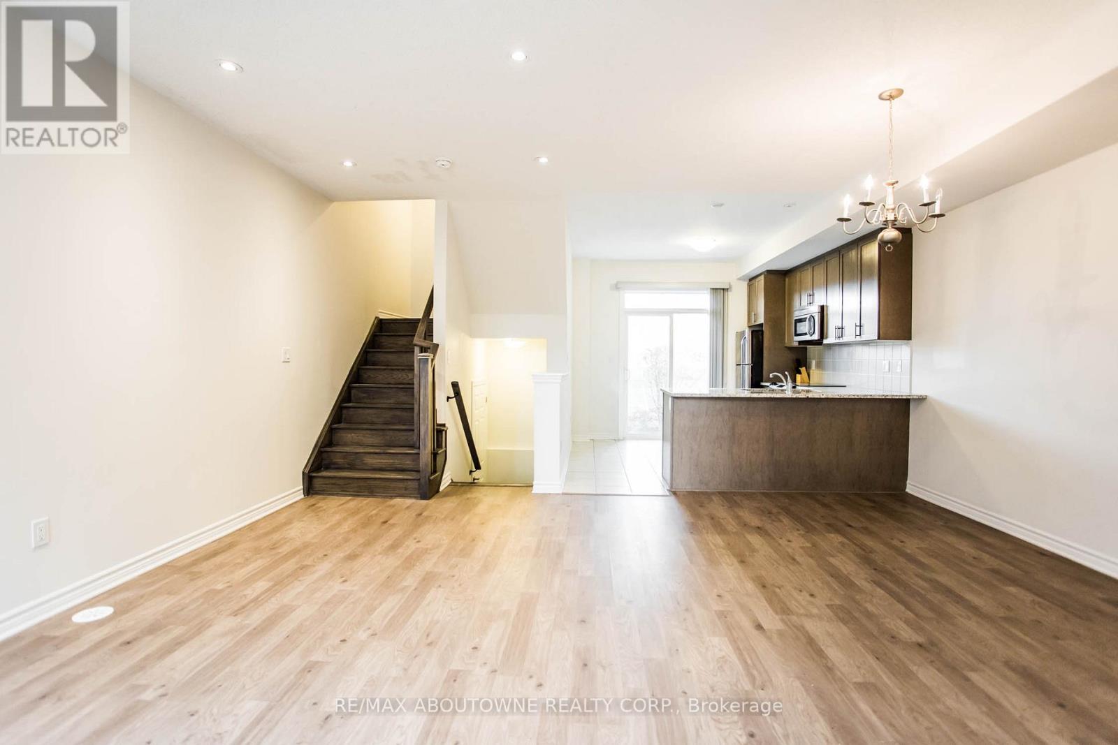 A spacious room with wooden flooring and a staircase leading to another level.