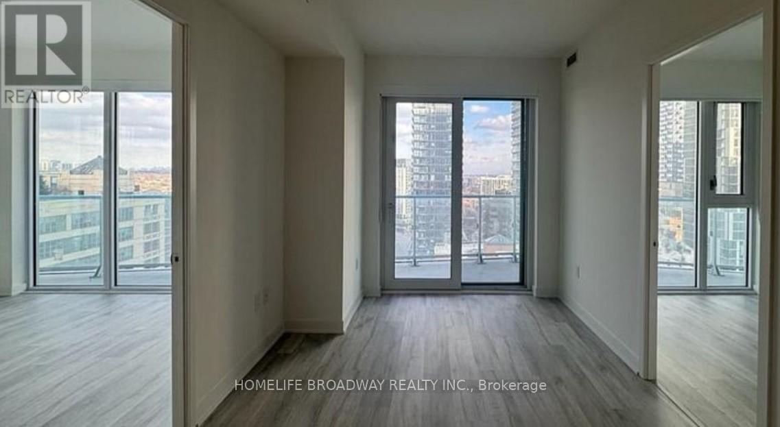 A spacious room with wooden floors and large windows overlooking a cityscape.