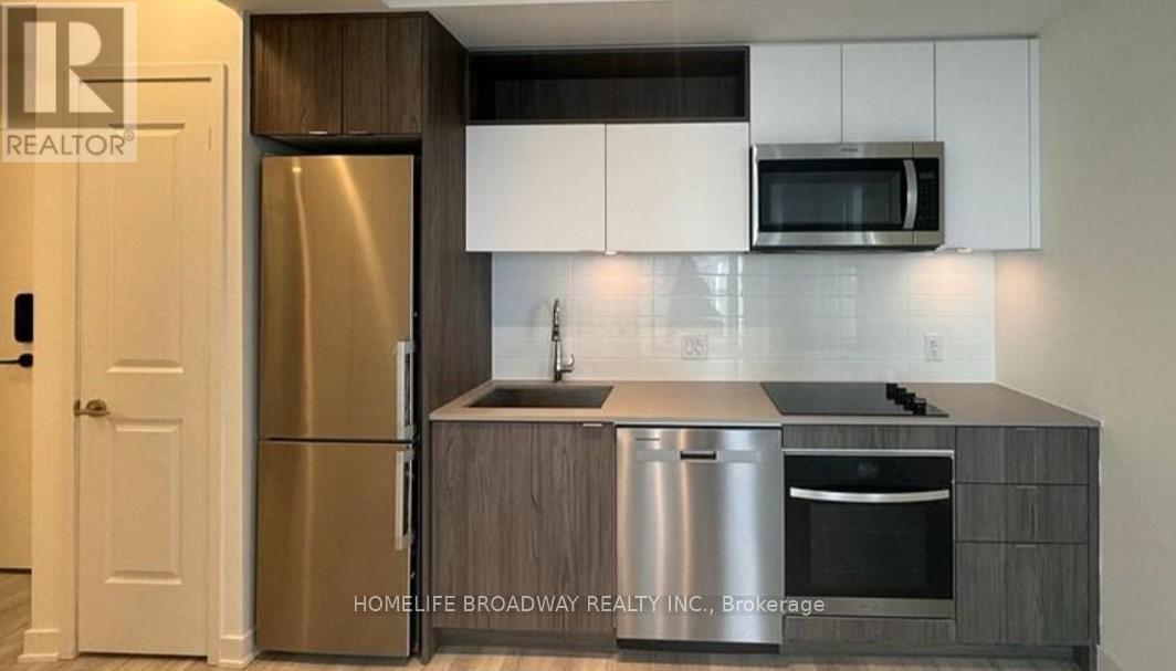 A kitchen with a refrigerator, sink, and oven.
