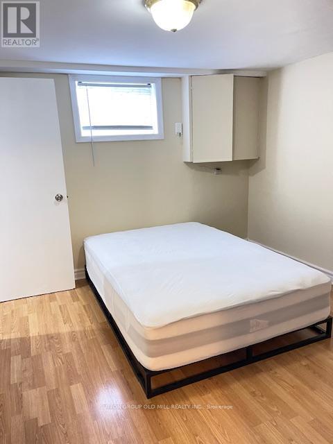 A bedroom with a bed, wooden floor, and a window.