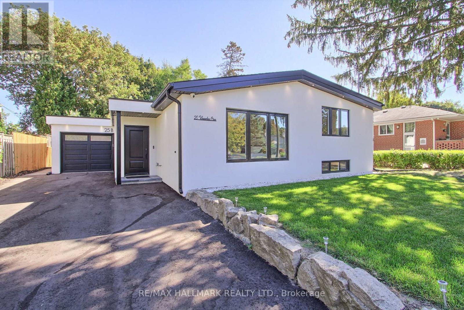 A modern house with a white exterior and a stone wall in front.
