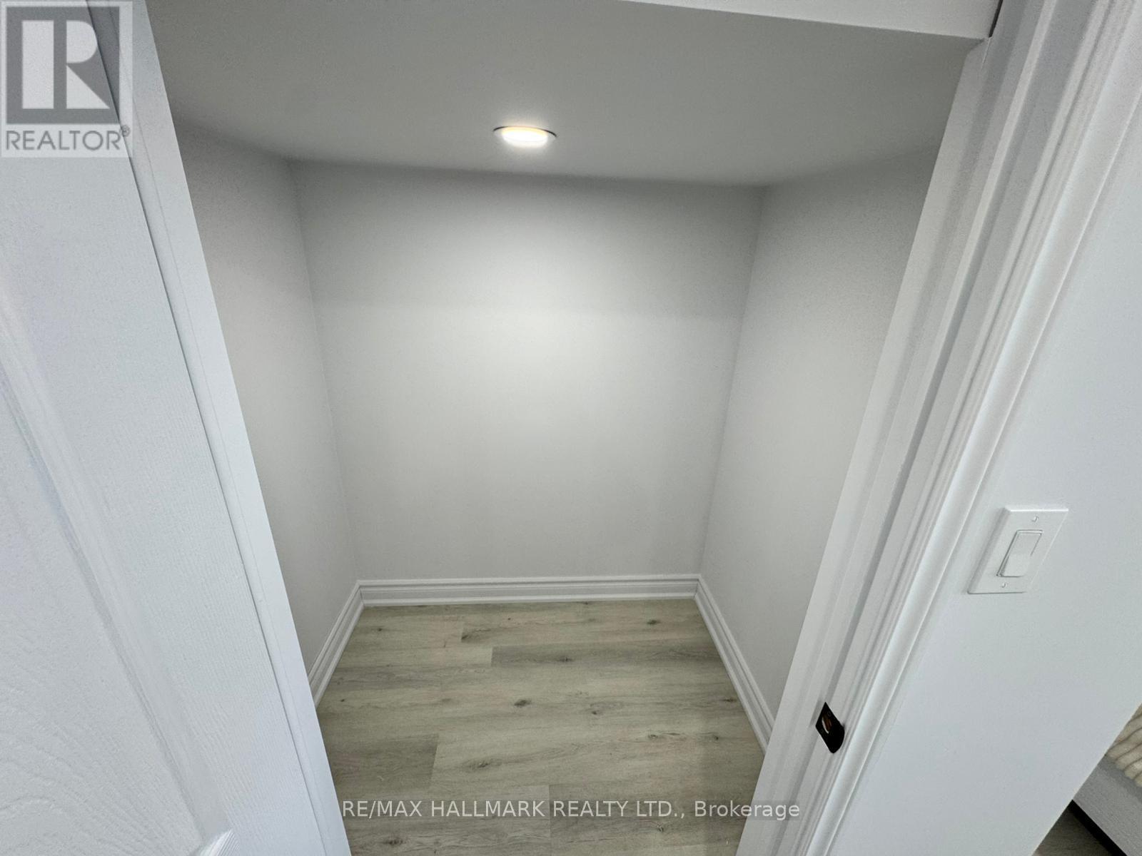 A white door with a black handle is open, revealing a small bedroom with a bed and a nightstand.