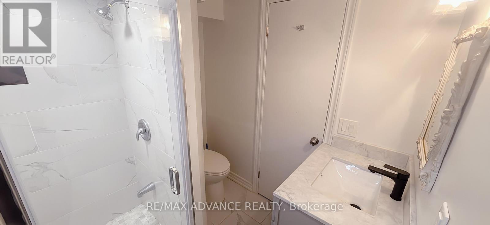 A white bathroom with a marble shower and toilet.