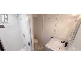 A white bathroom with a marble shower and toilet.