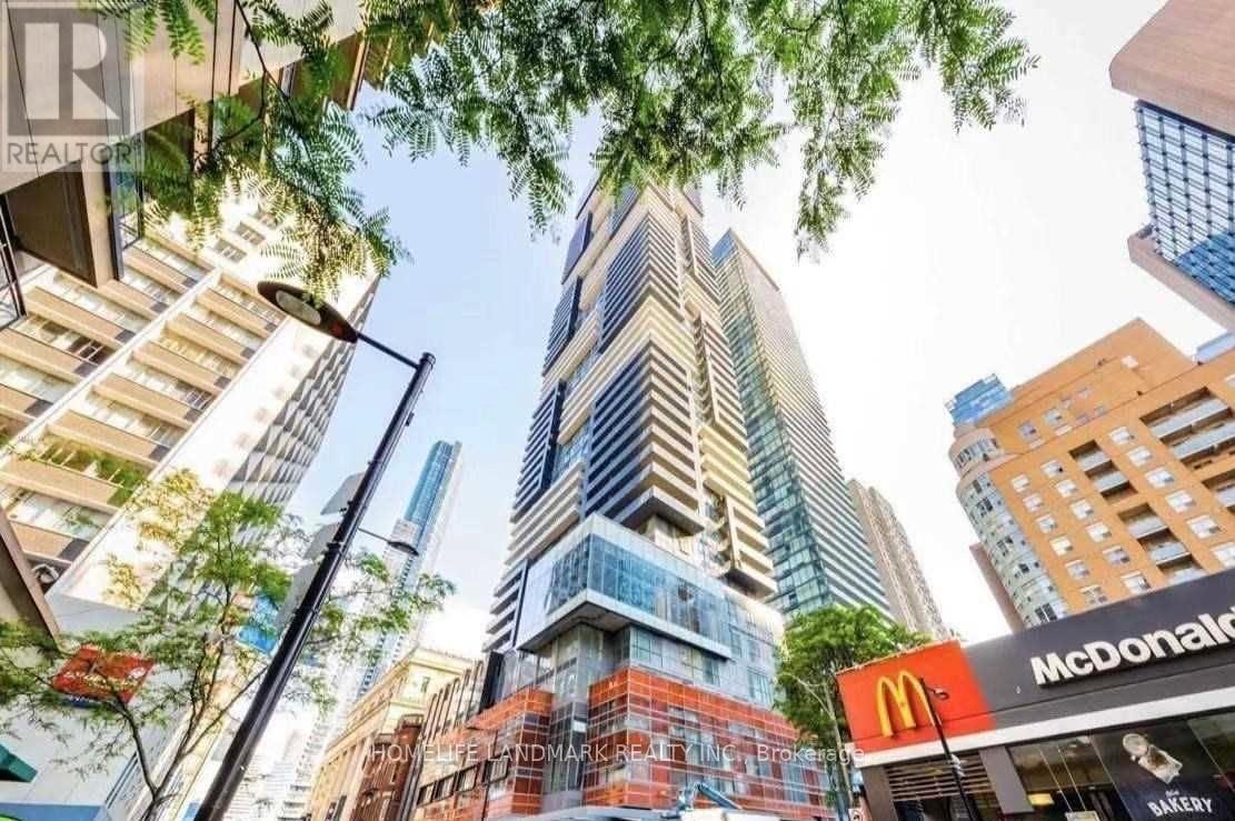 A tall building with a glass facade stands in the middle of a city street.