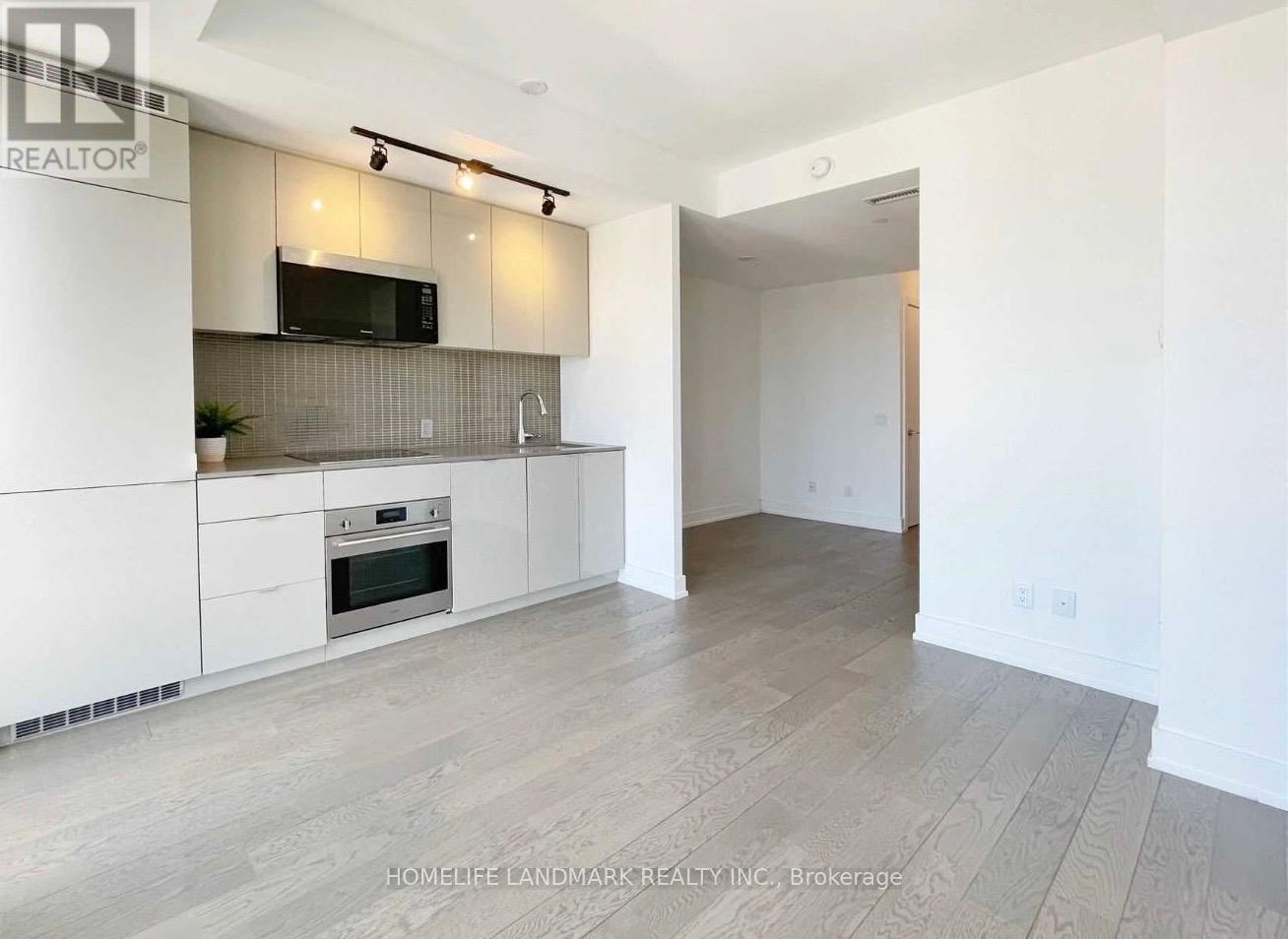 A modern kitchen with white cabinets and a wooden floor.