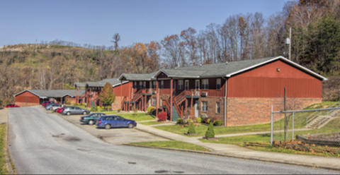 A long building with a green roof sits on a street.