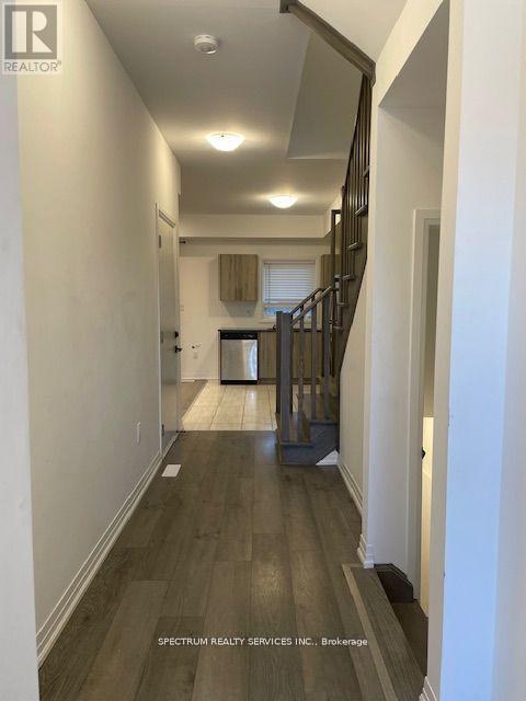 A hallway with wood floors and a staircase.