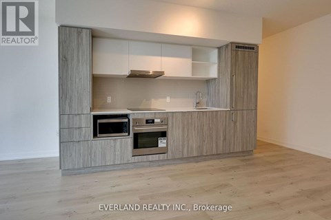 A kitchen with a wooden cabinet and a microwave oven.