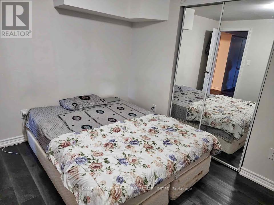 A bedroom with a bed, a mirror, and a wall-mounted shelf.