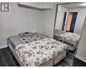 A bedroom with a bed, a mirror, and a wall-mounted shelf.