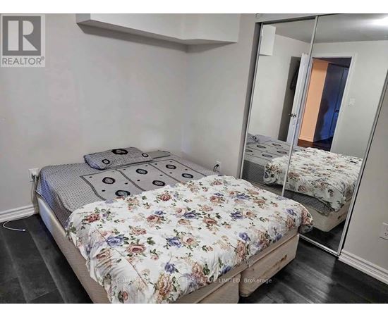 A bedroom with a bed, a mirror, and a wall-mounted shelf.