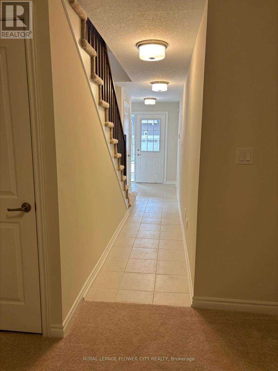 A hallway with a carpeted floor, a white door, and a staircase with a railing.