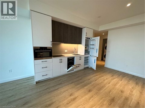 A well-lit kitchen with white cabinets and a wooden floor.