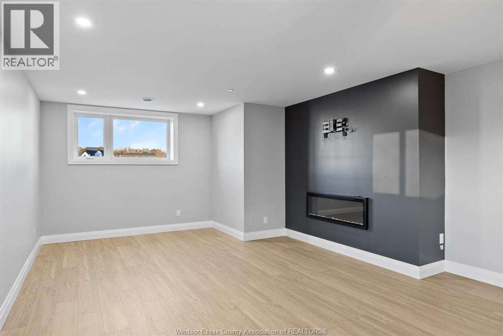 A spacious room with a fireplace and a window overlooking a field.