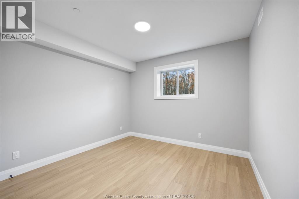 A room with a wooden floor and a window showing trees outside.