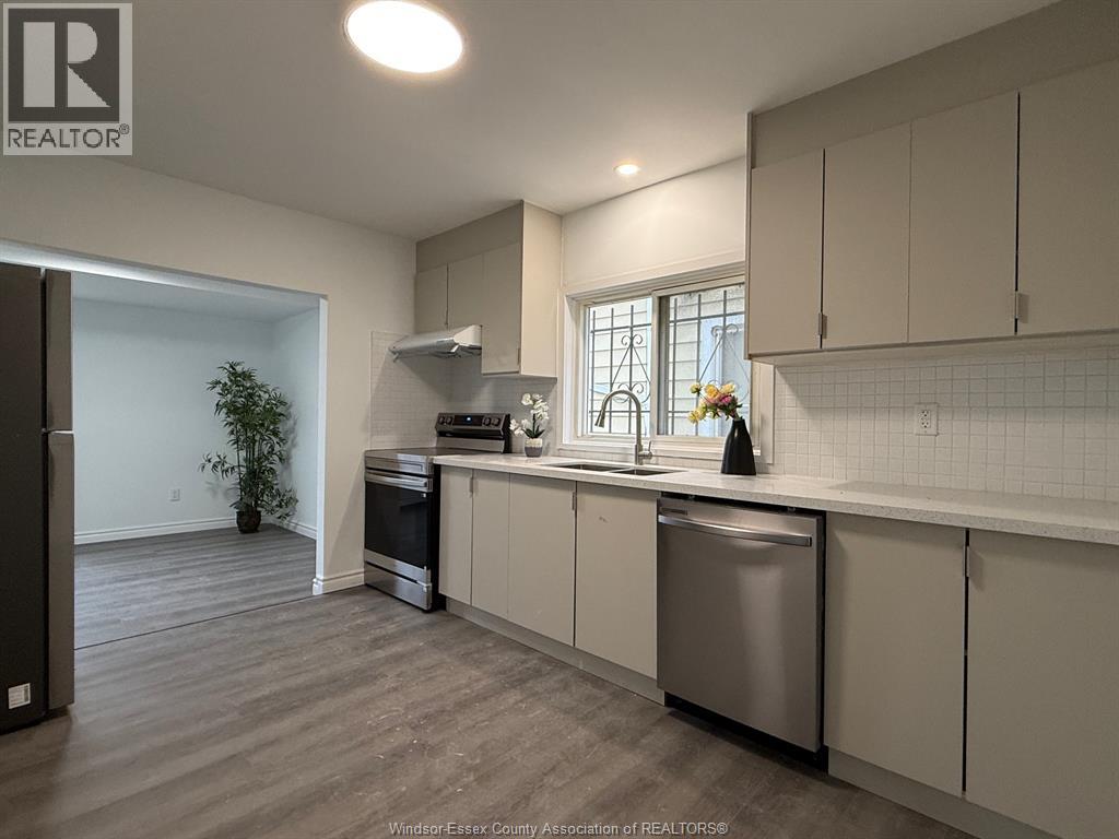 A kitchen with a stainless steel dishwasher and a window.