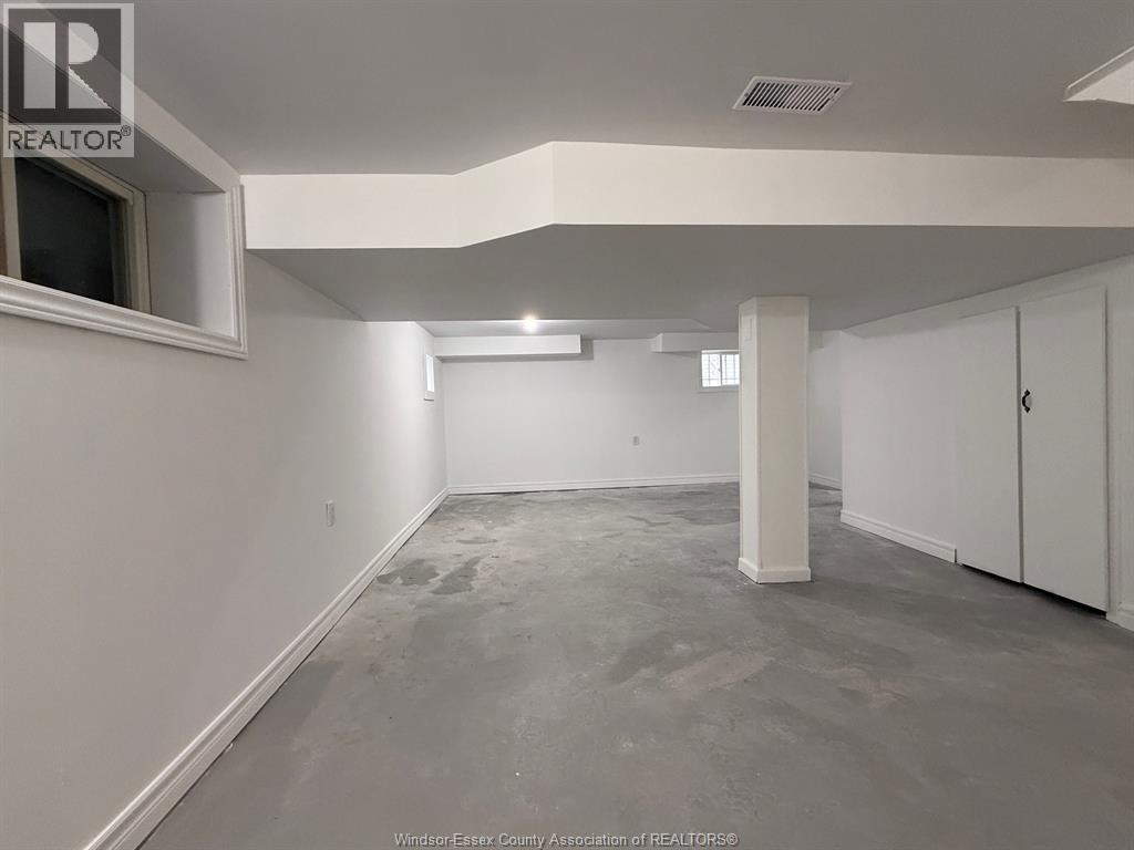 A spacious room with white walls and a grey floor.