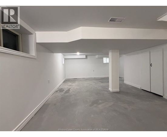 A spacious room with white walls and a grey floor.