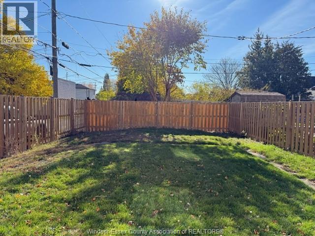 A backyard with a wooden fence and green grass.