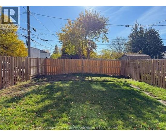 A backyard with a wooden fence and green grass.