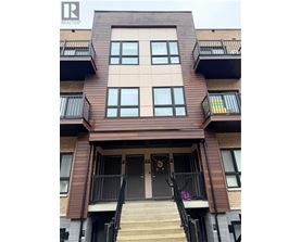 A brown building with a black railing and a black door.