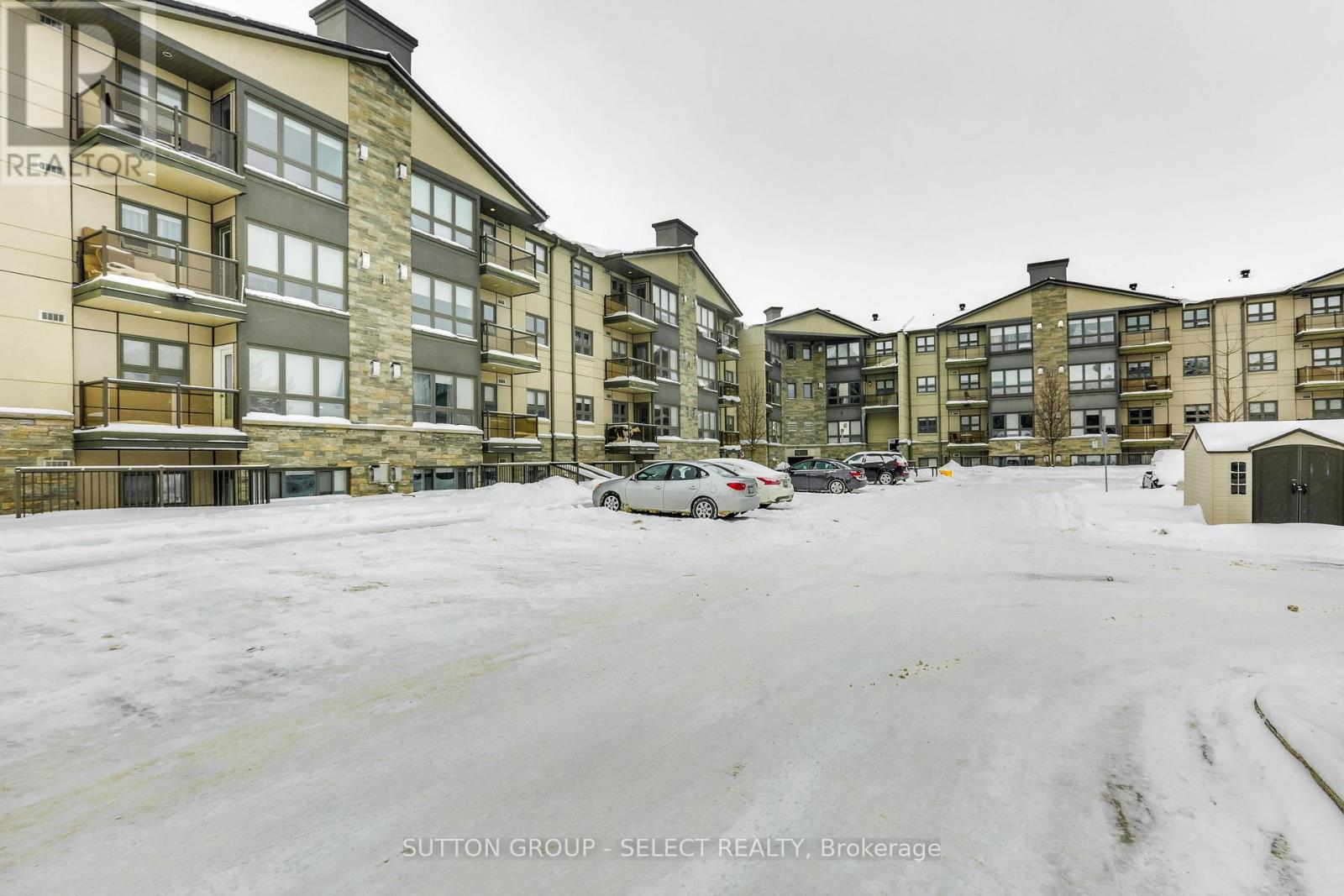 A snowy parking lot in front of apartment buildings.