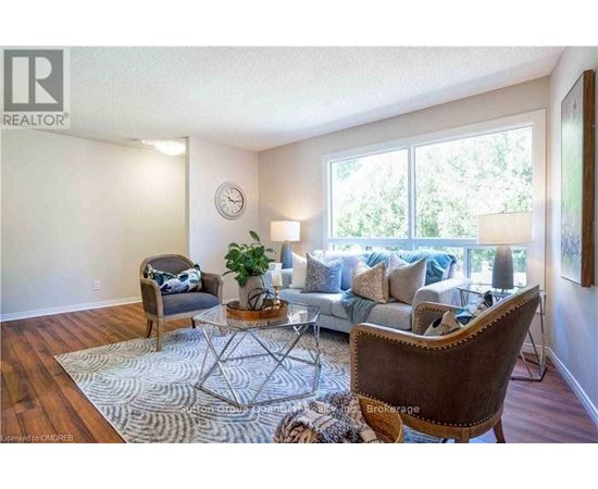 A living room with a brown chair and a glass table with a plant on it.