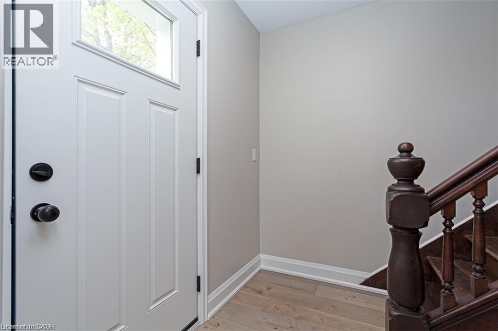 A white door with a black handle is on the left and a wooden staircase is on the right.