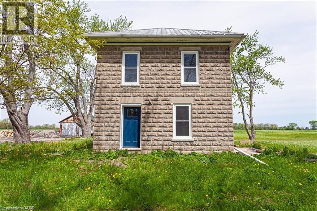 A small stone house with a blue door stands alone in a grassy field.
