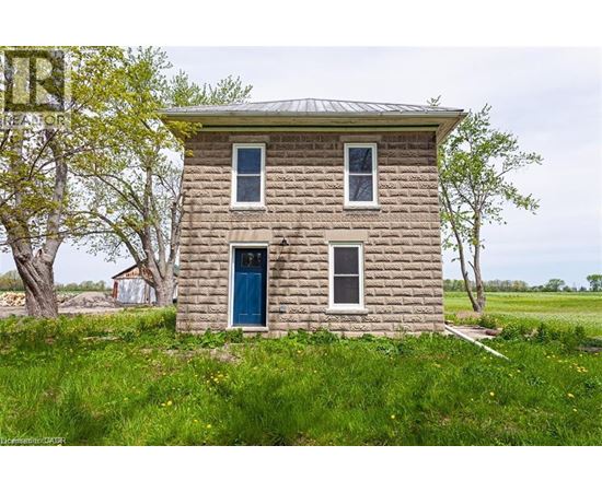 A small stone house with a blue door stands alone in a grassy field.
