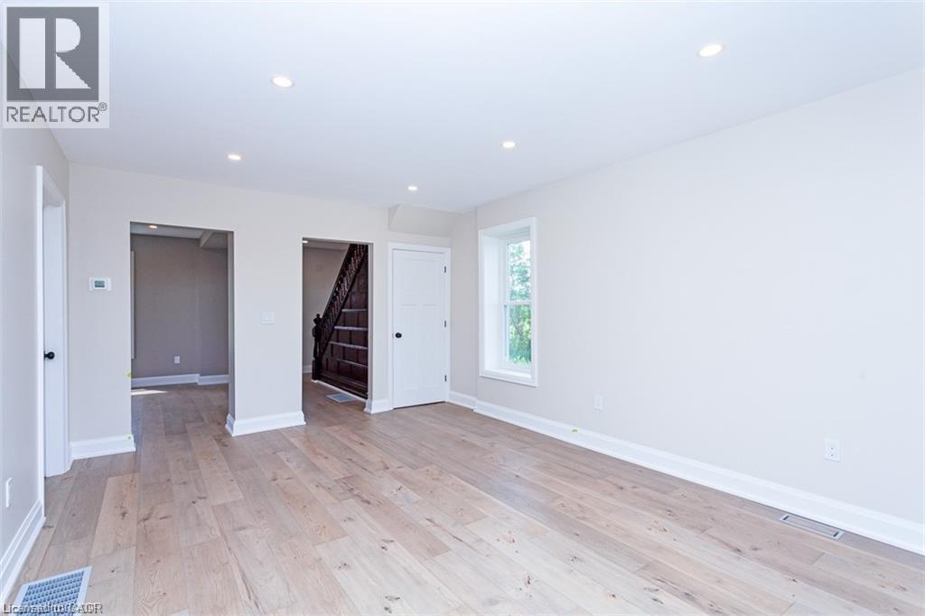 A spacious room with wooden flooring and white walls.