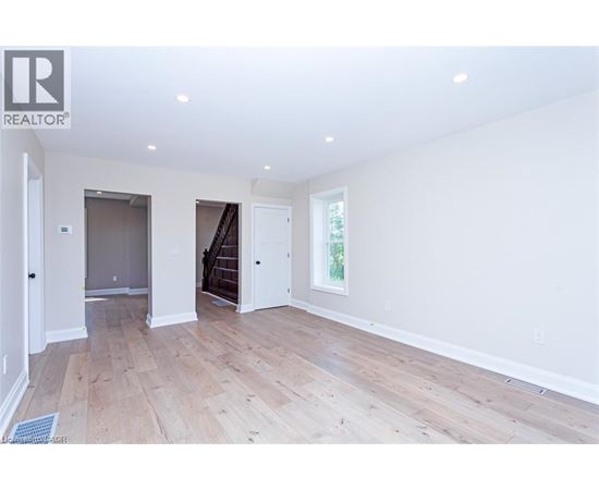 A spacious room with wooden flooring and white walls.