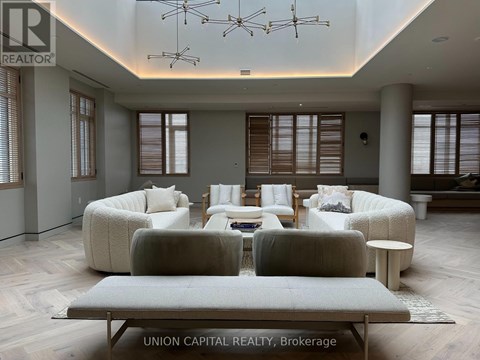 A spacious living room with a grey sofa set and a wooden floor.