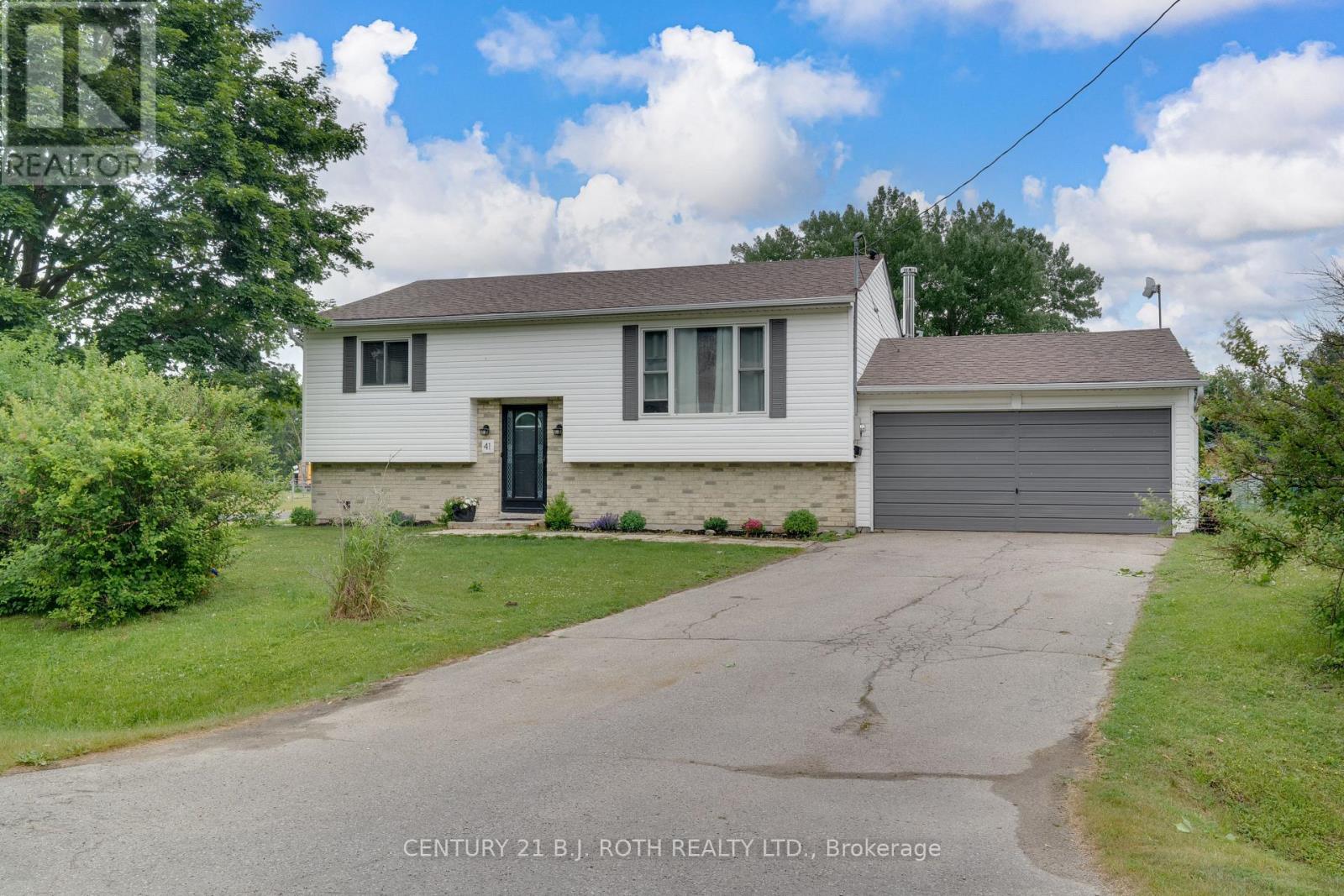A white house with a grey garage door is for sale.