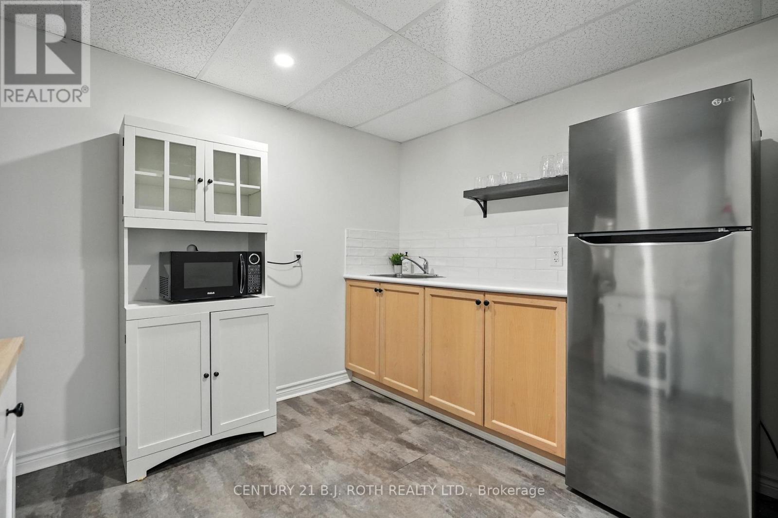 A kitchen with white cabinets and a stainless steel refrigerator.