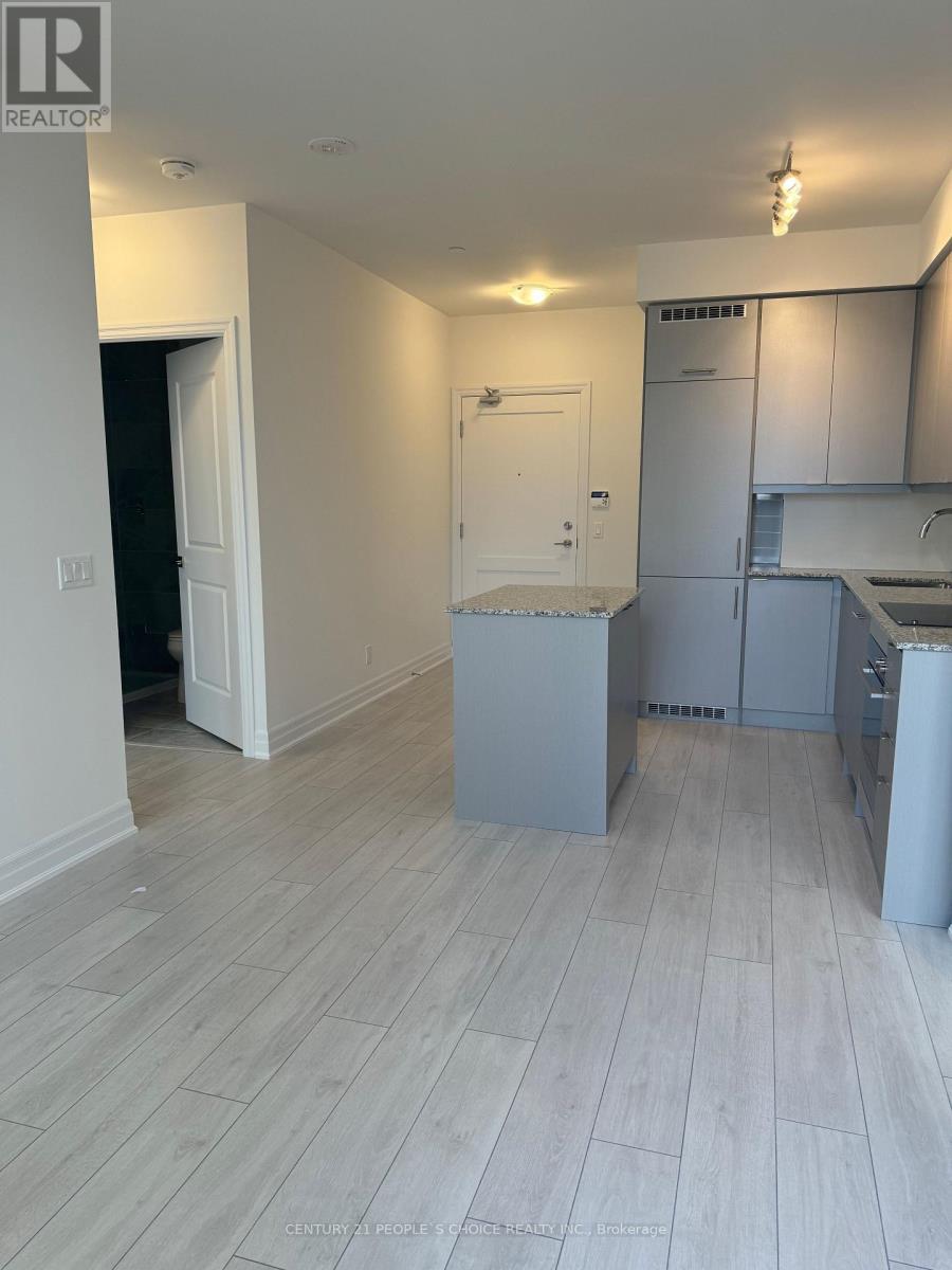 A realtor photo of a kitchen and living room with white cabinetry and light wood flooring.