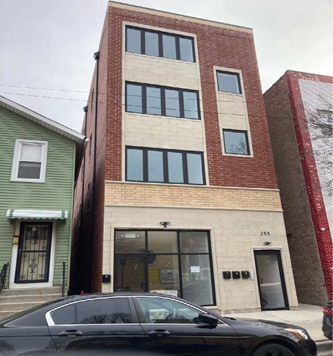 A black car is parked in front of a building with a red brick facade.