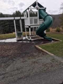 A playground with a green slide and a white wooden structure.