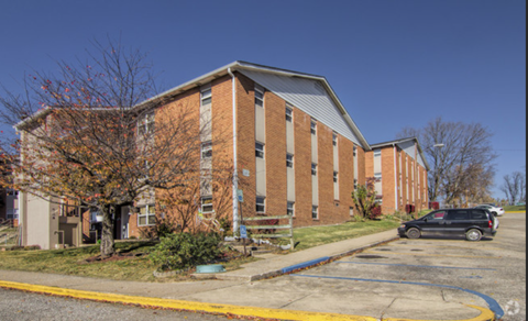 A brick building with a parking lot in front.