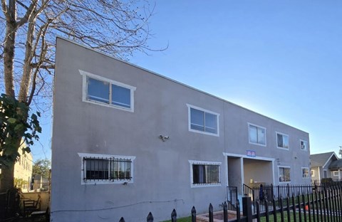 A grey building with a black fence in front.