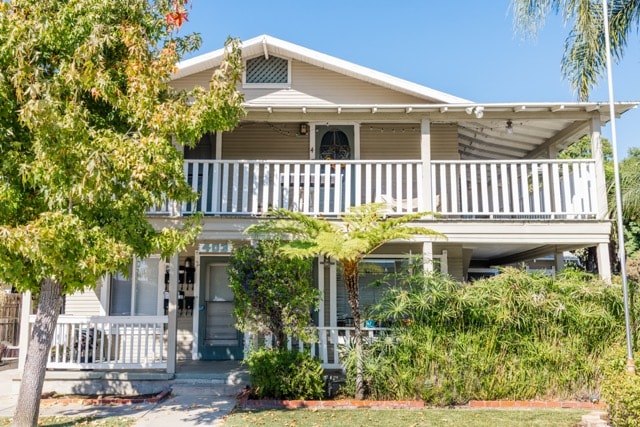 A house with a white porch and a tree in front.