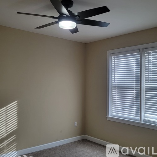 A room with a ceiling fan and a window with blinds.