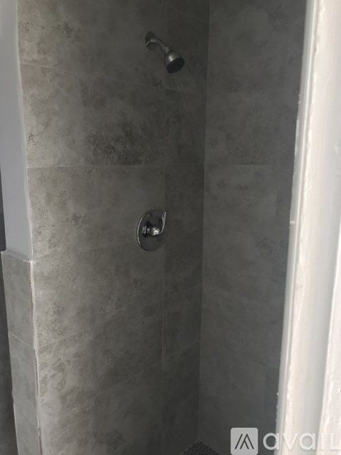 A shower with a white curtain and a black handle.