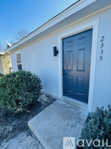 A house numbered 2335 with a dark blue door and a small bush in front.