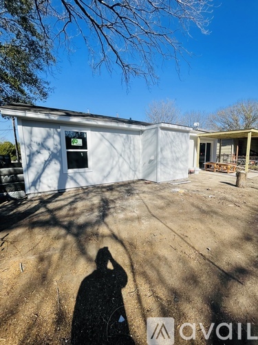 A person is taking a photo of a white building with a shadow cast on the ground.