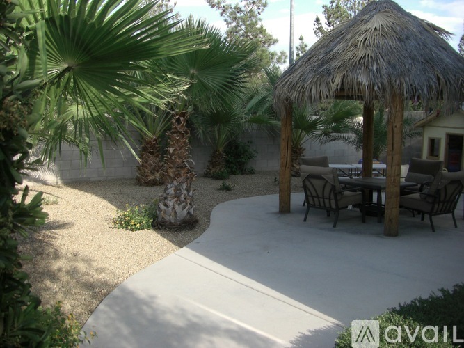 A patio with a table and chairs under a thatched roof.