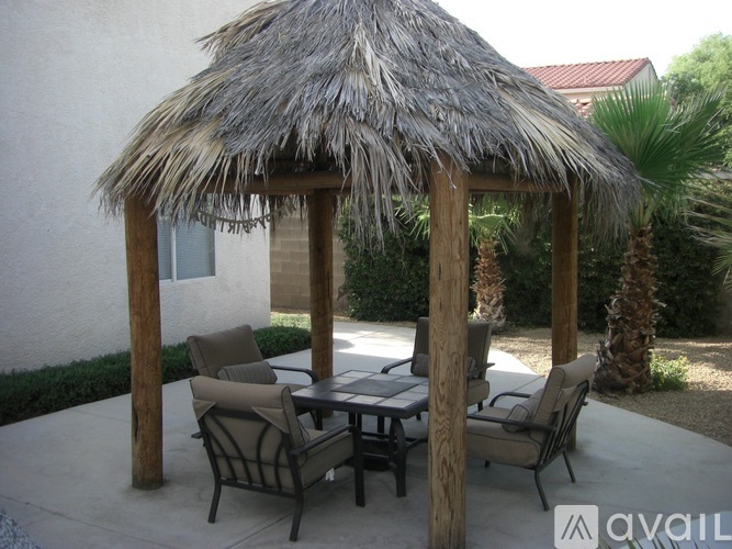 A patio with a table and chairs under a thatched roof.