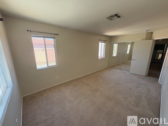 A spacious room with beige carpeting and a sliding glass door.