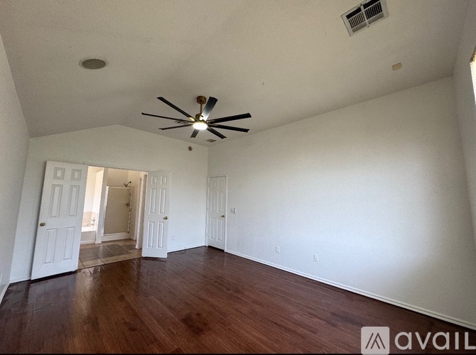 A spacious room with a ceiling fan and wooden flooring.